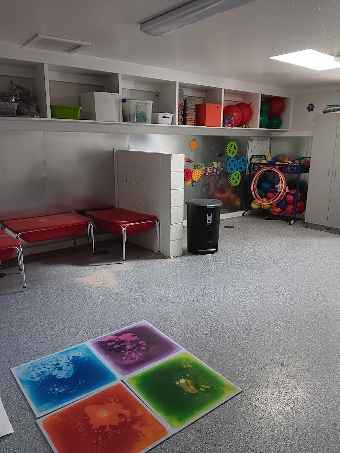 Playroom with fluid-filled floor tiles and shelves of toys and play equipment