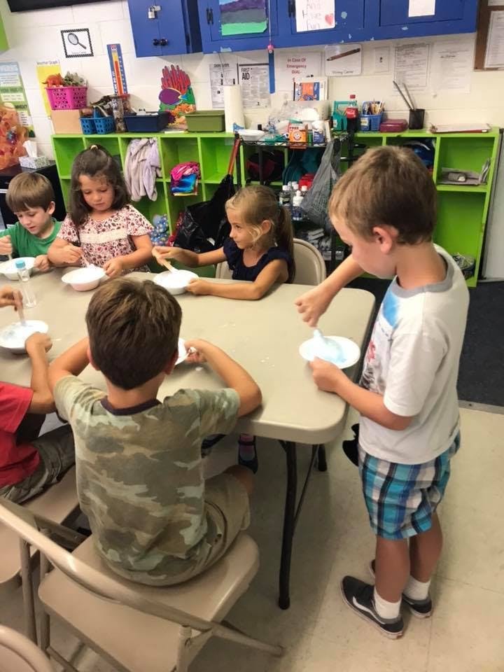 Children at a table with bowls and spoons in a classroom
