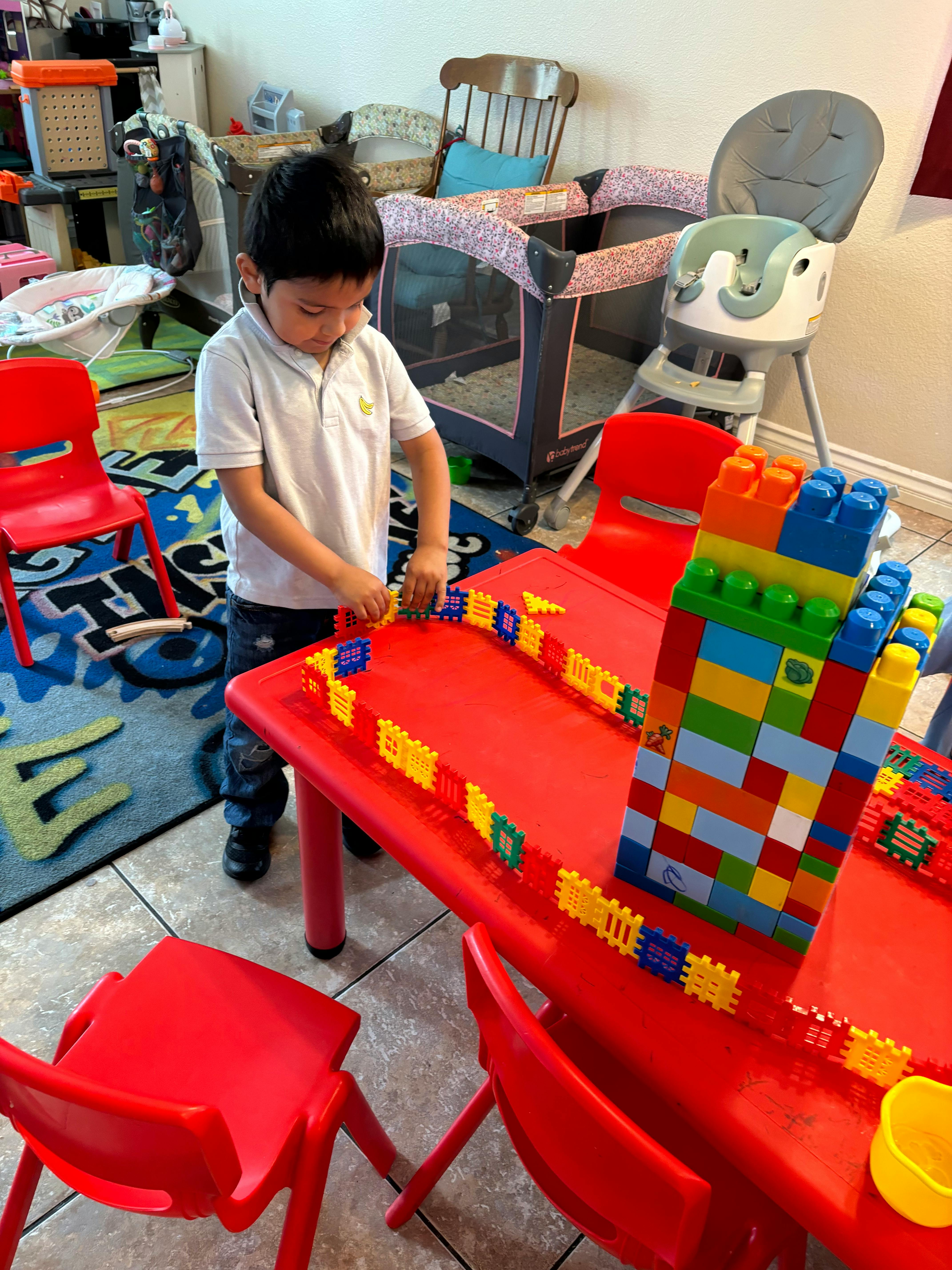 Child playing with colorful building blocks at a red table