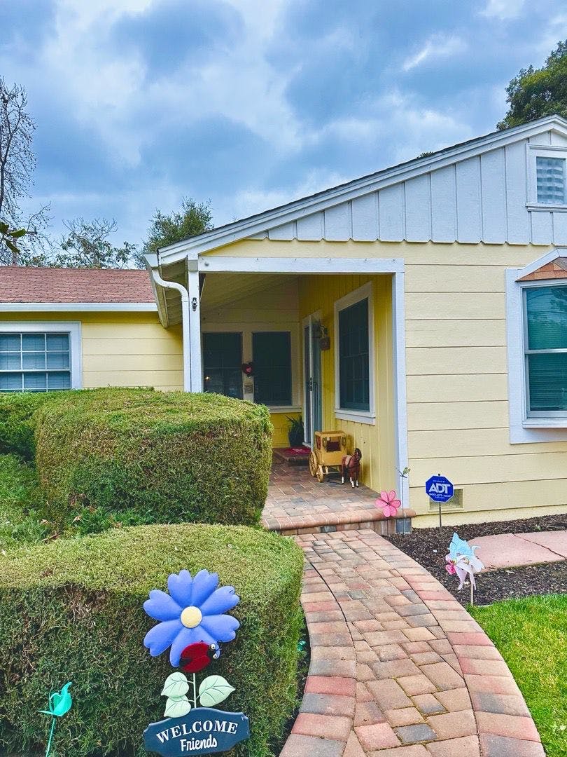 Yellow house with a brick pathway leading to the front porch