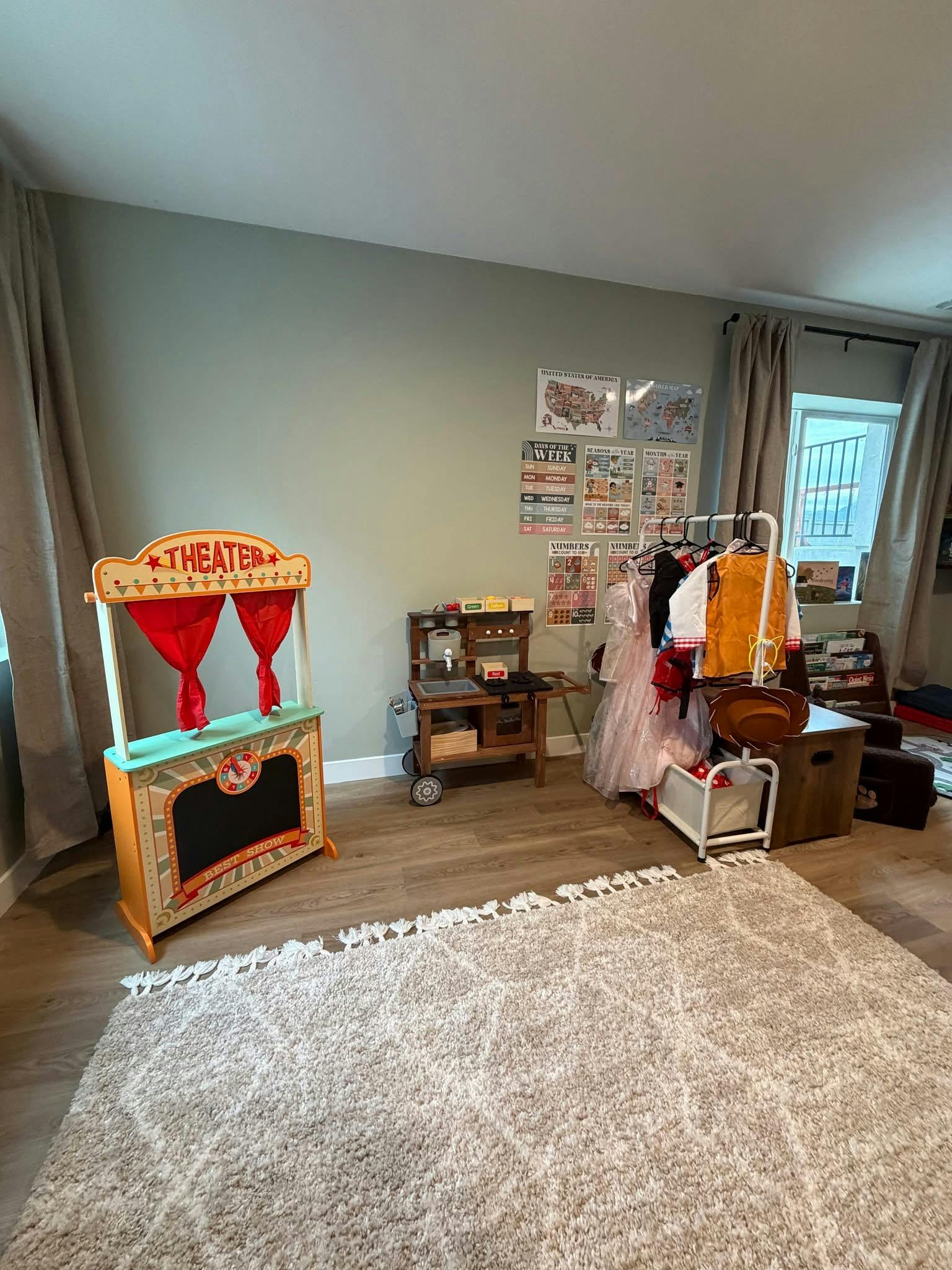 Playroom with a toy theater, dress-up clothes, and a rug