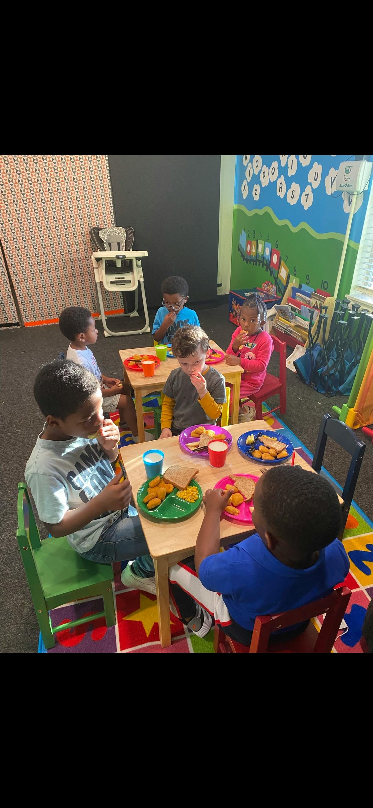 Children eating at small tables in a classroom