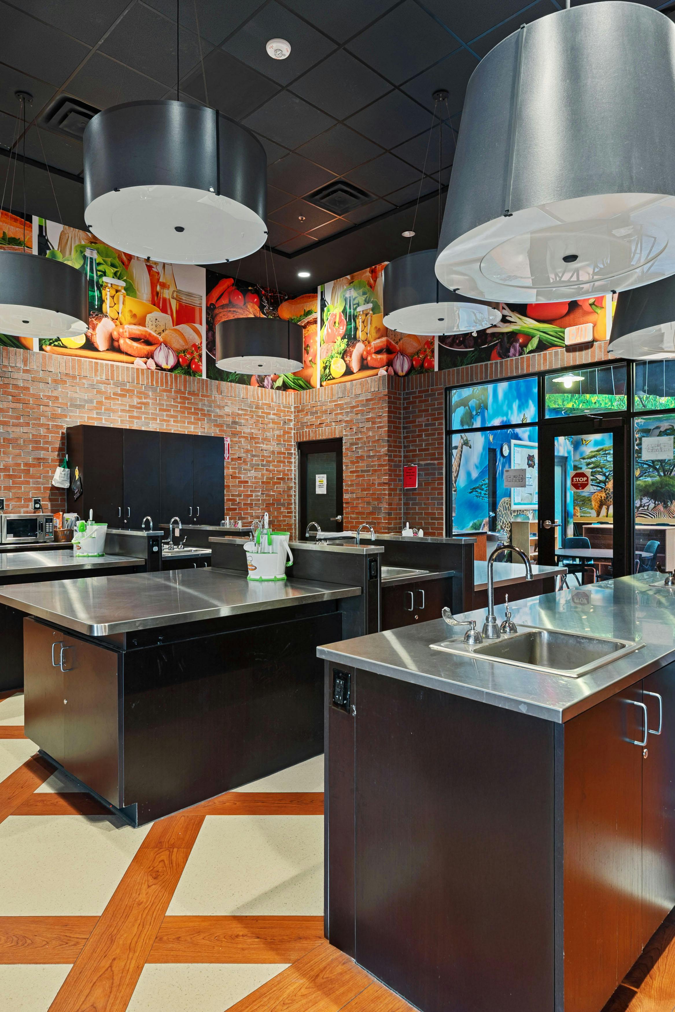 A cooking classroom with multiple stainless steel counters and sinks