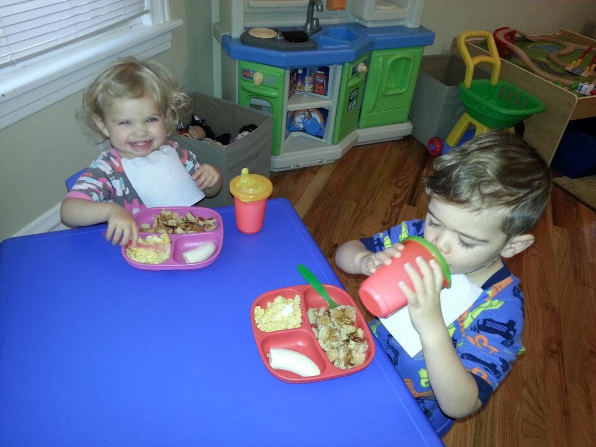 Two children eating at a blue table