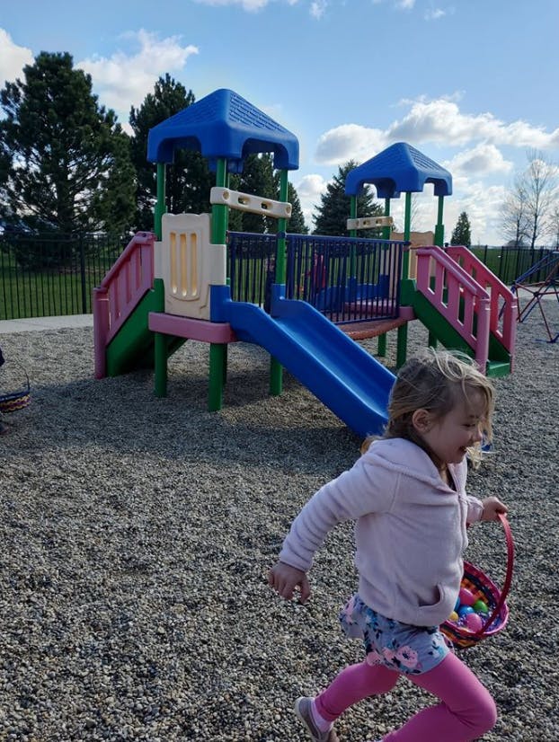 Child running with a basket of eggs on a playground