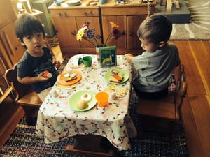 Two children sitting at a small table with plates of food
