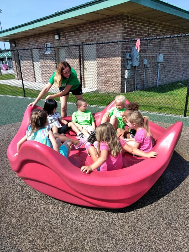 Adult and children playing in a pink boat-shaped playground toy