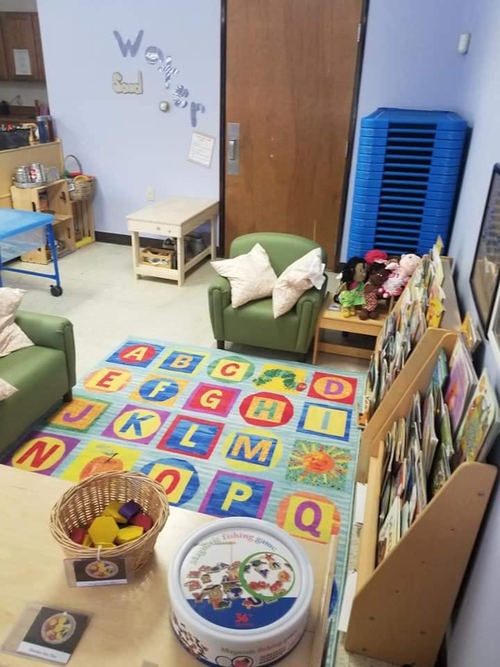 Classroom with an alphabet rug, green chairs, and a bookshelf