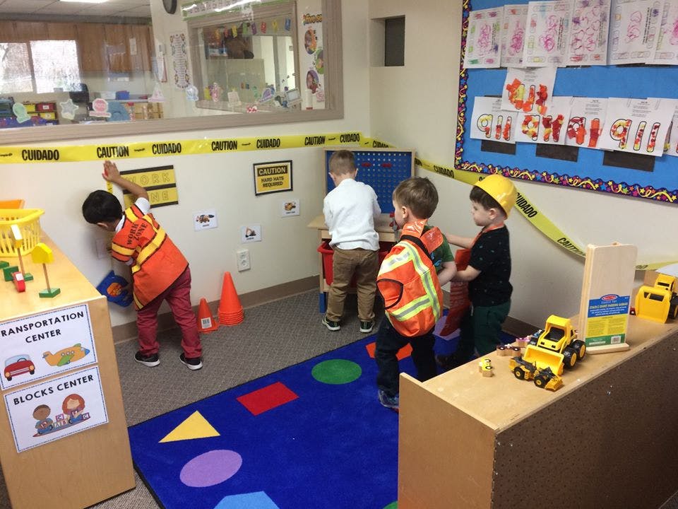 Children playing in a classroom with construction-themed toys