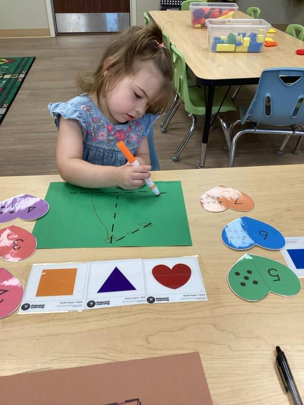 Child coloring on paper at a table with learning materials