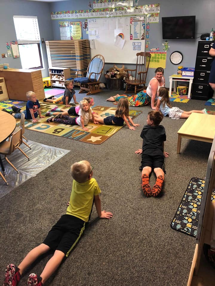 Children and an adult lying on the floor in a classroom