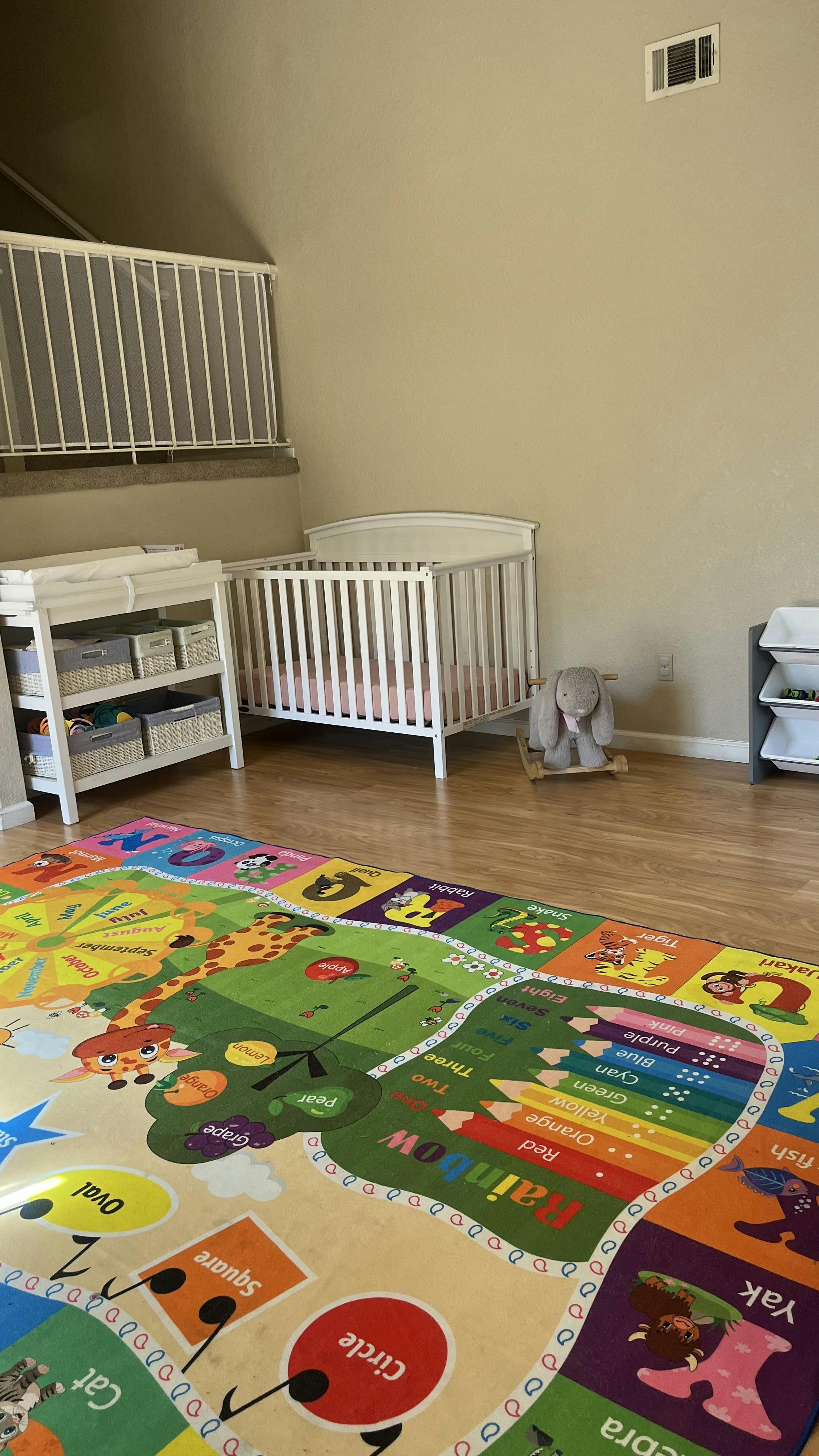 Nursery room with a crib, changing table, and colorful alphabet rug