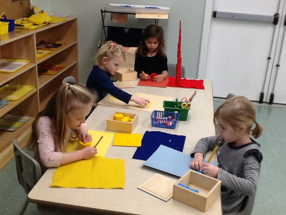 Four children working at a table with craft supplies