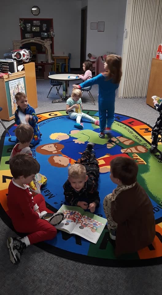 Children sitting and lying on a colorful rug in a classroom