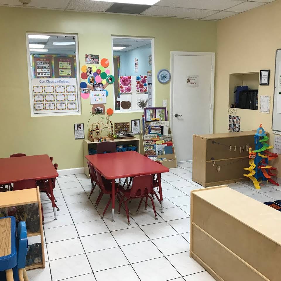 Classroom with red tables and chairs, shelves, and wall decorations