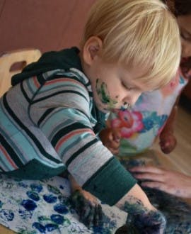 Child with paint on face and hands
