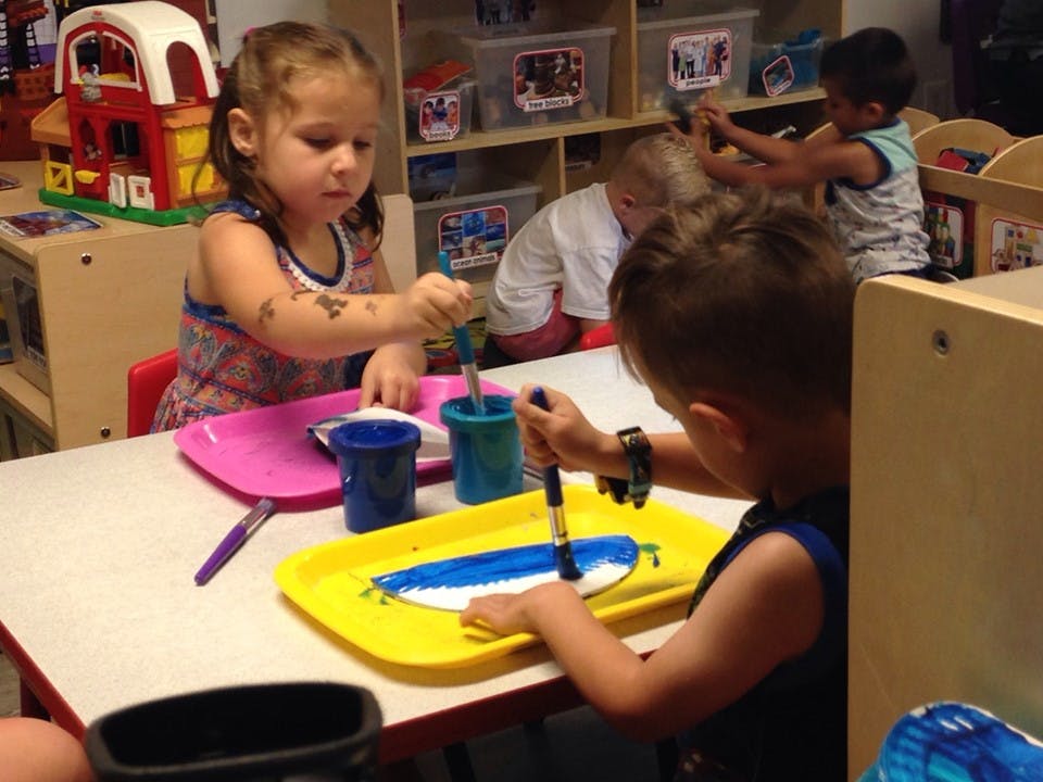 Children painting at a table in a classroom