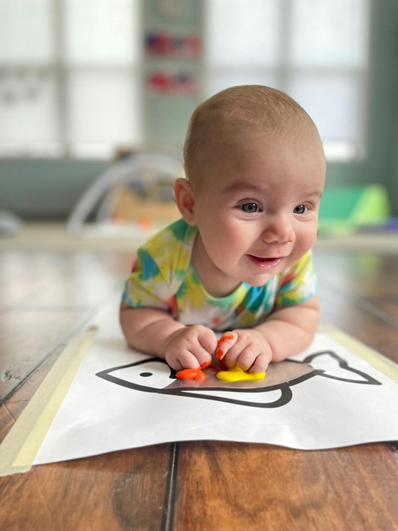 Child on stomach playing with colorful shapes on a fish drawing