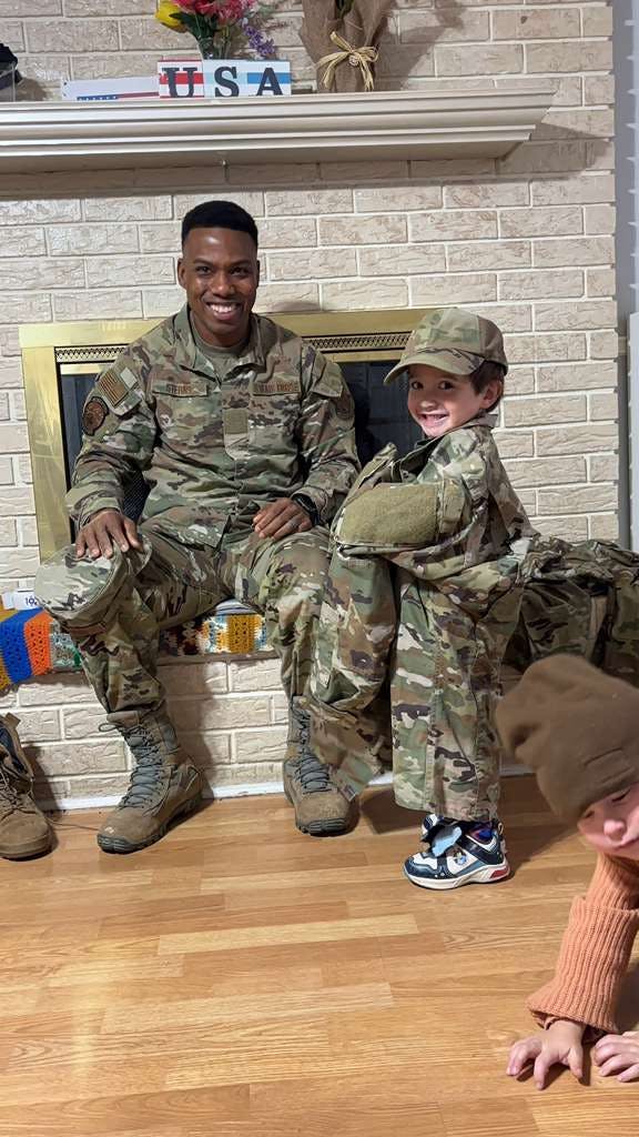 A person in military uniform and a child wearing oversized camouflage clothing