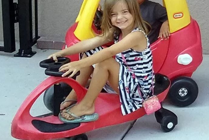 Child sitting in a red toy car