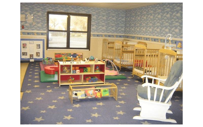 A nursery room with cribs, toys, and a rocking chair