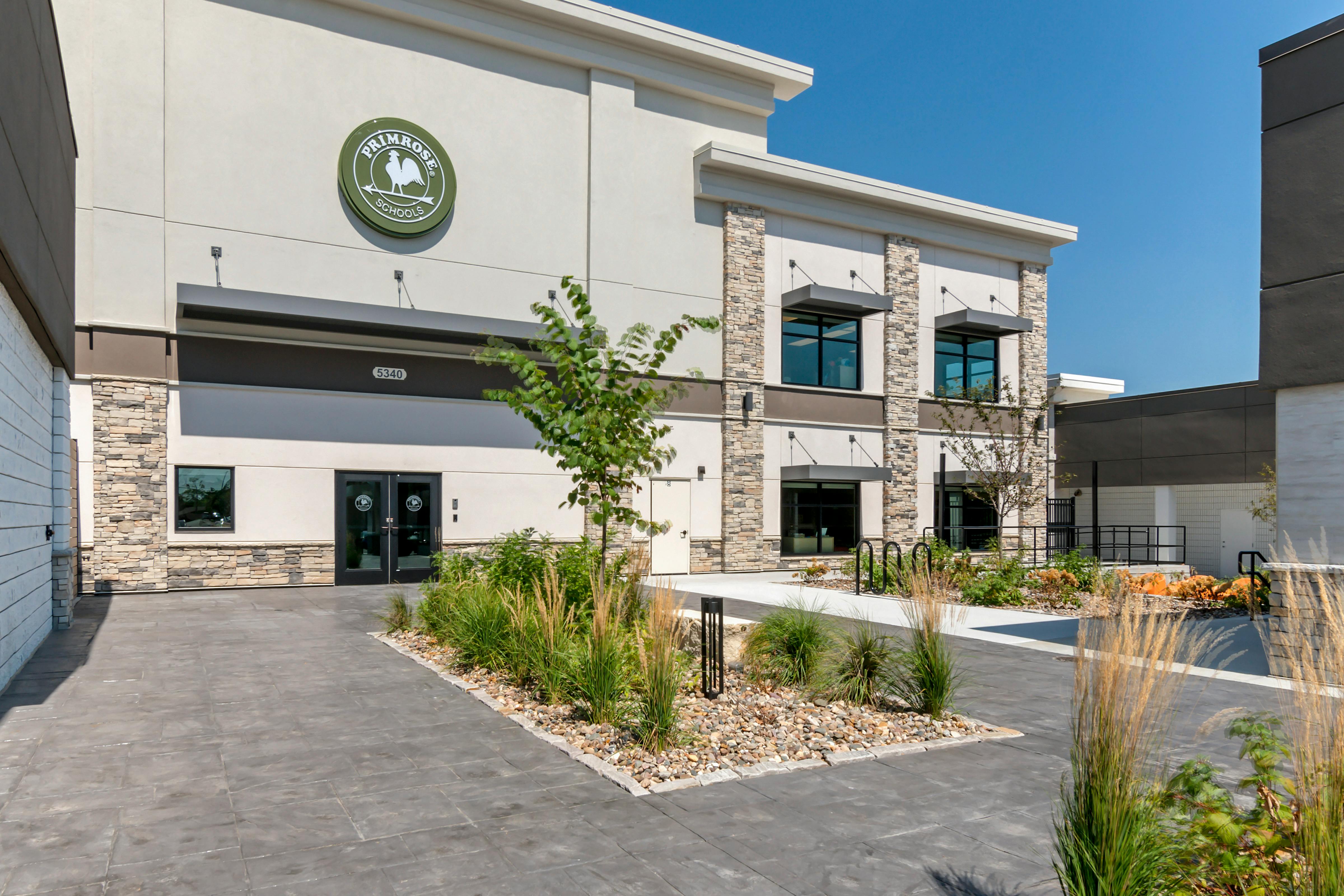 Exterior of Primrose School building with a green logo, stone accents, and landscaping