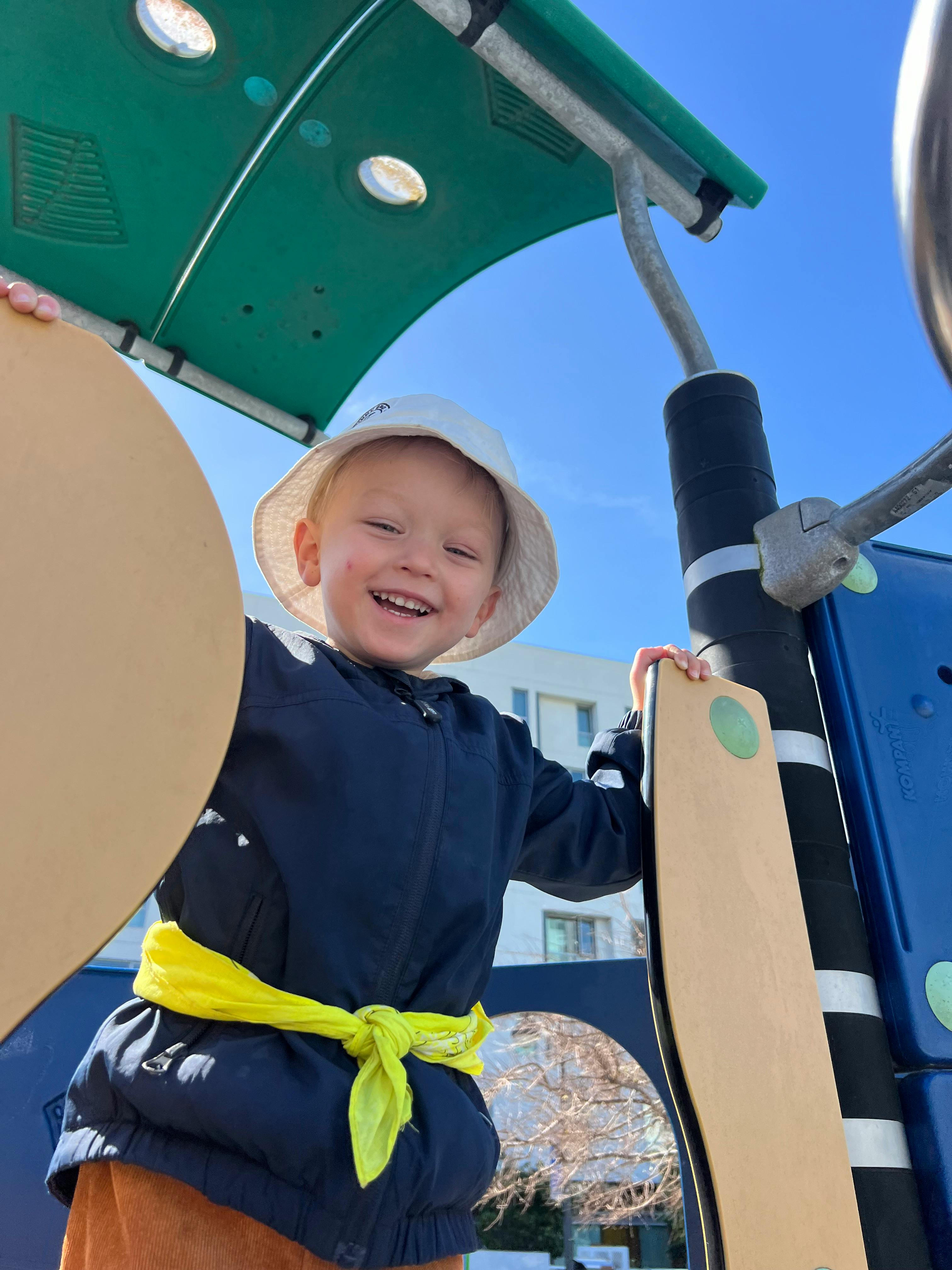 Child in a hat on a playground structure at a playground