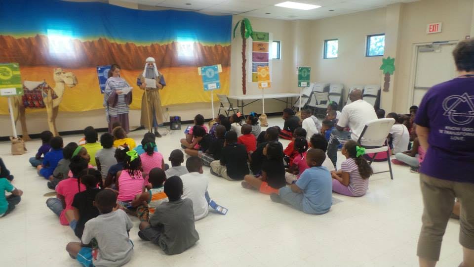 Children sitting on the floor watching two people in costumes