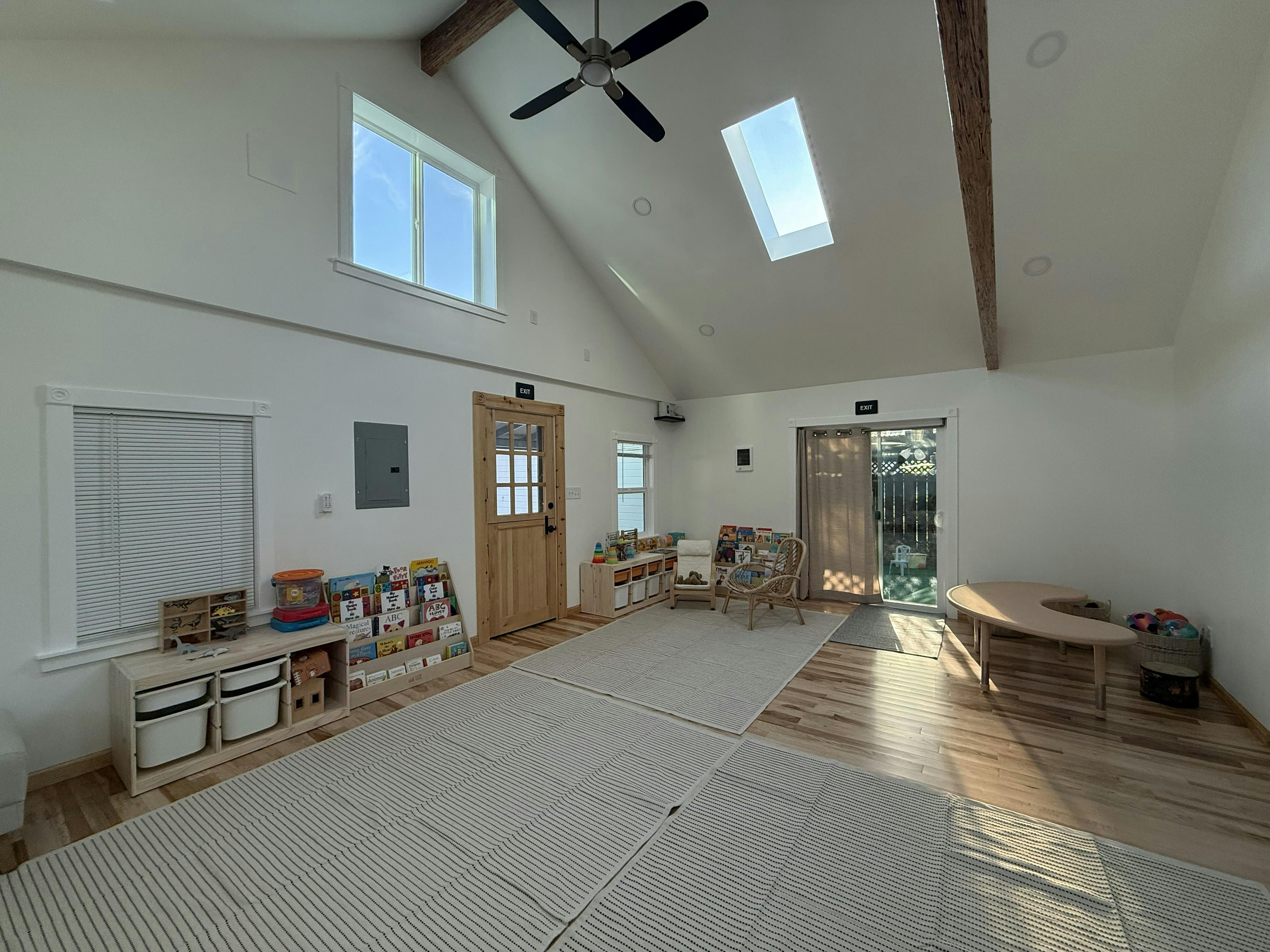 Room with vaulted ceiling, ceiling fan, skylights, and wooden doors