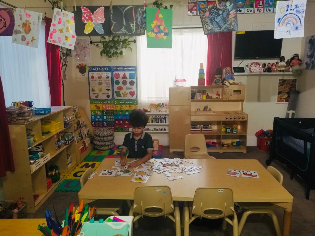 Child sitting at a table with cards in a classroom
