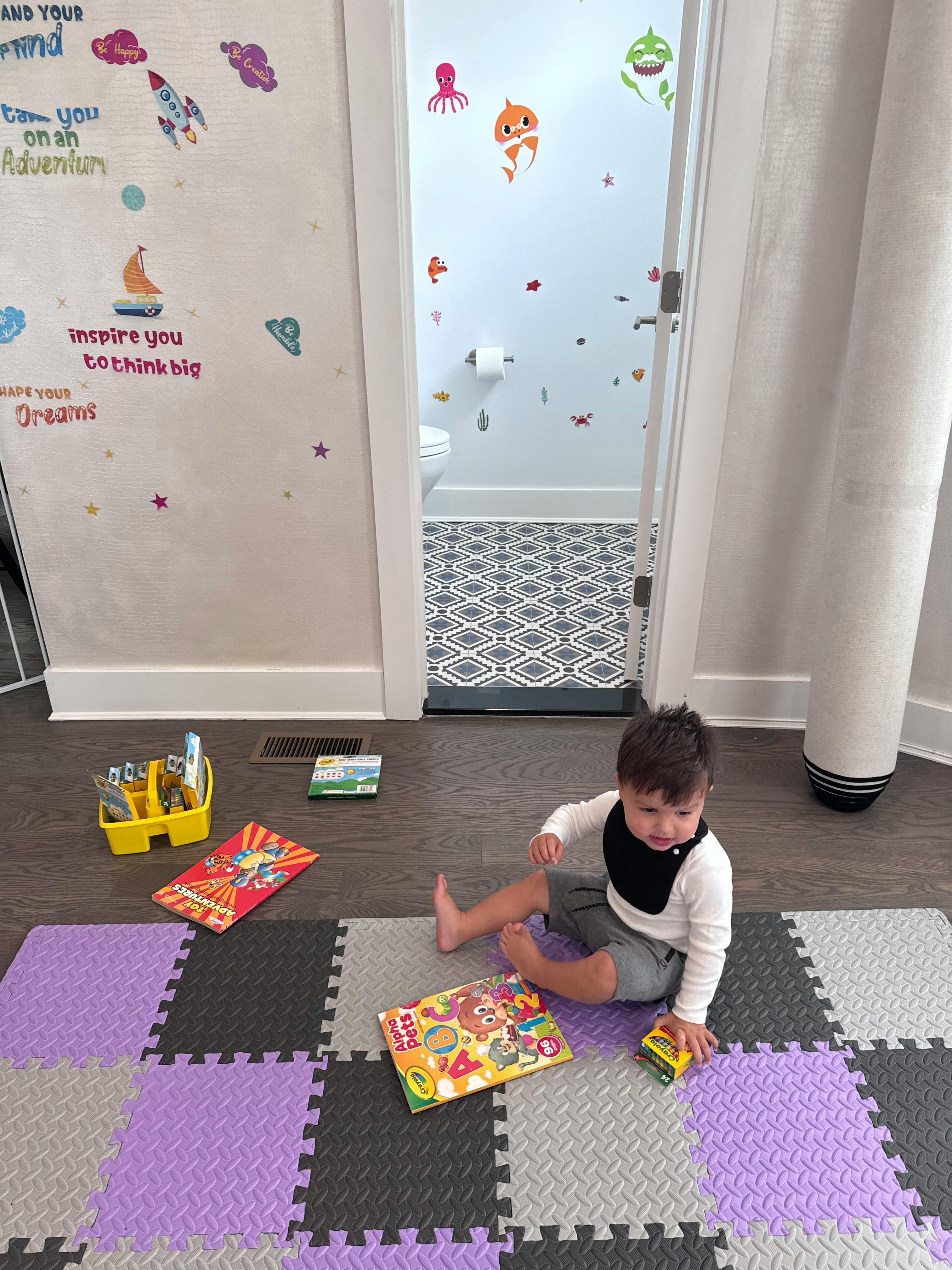 Child sitting on a playmat with a book