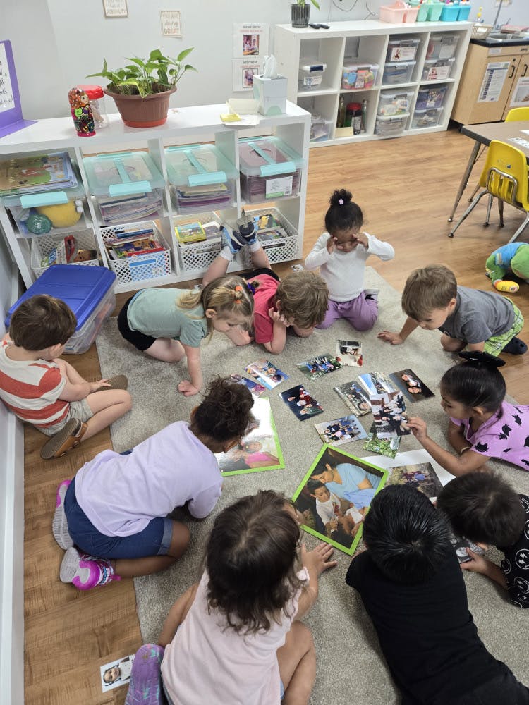 Children on a rug looking at pictures and books