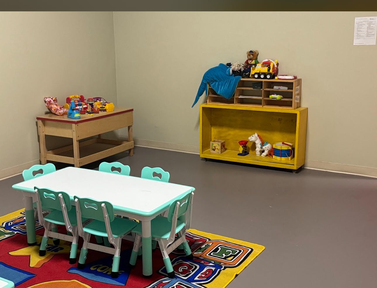Children's play area with small table and chairs, toys on shelves
