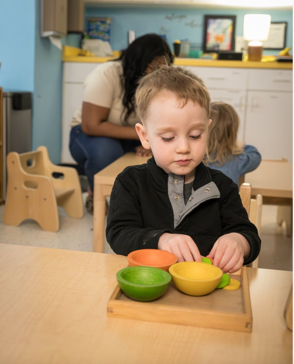 Child playing with colorful bowls at a table