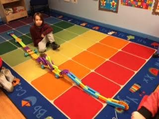 Child sitting on a colorful rug with a toy train