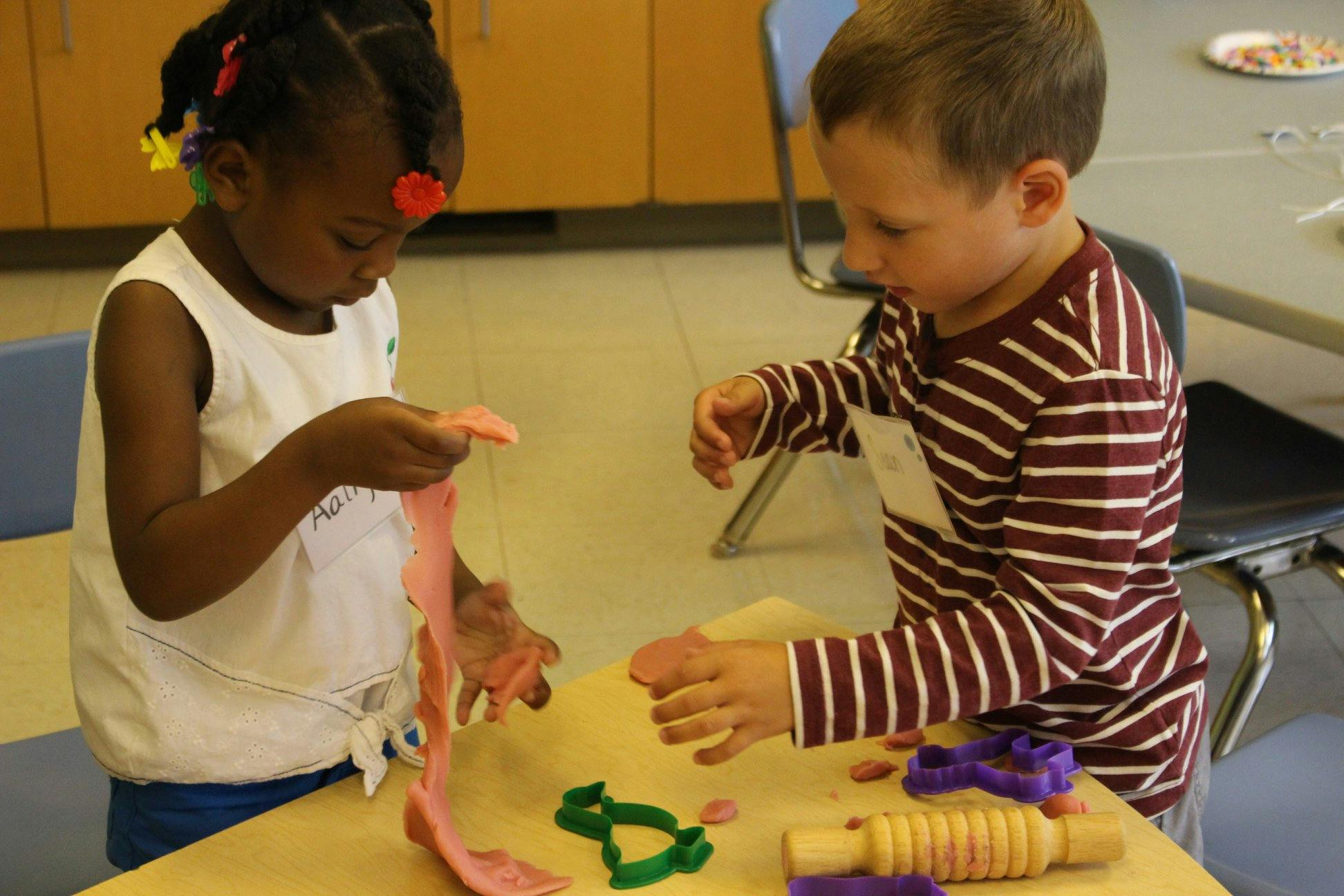 Two children playing with modeling clay at a table