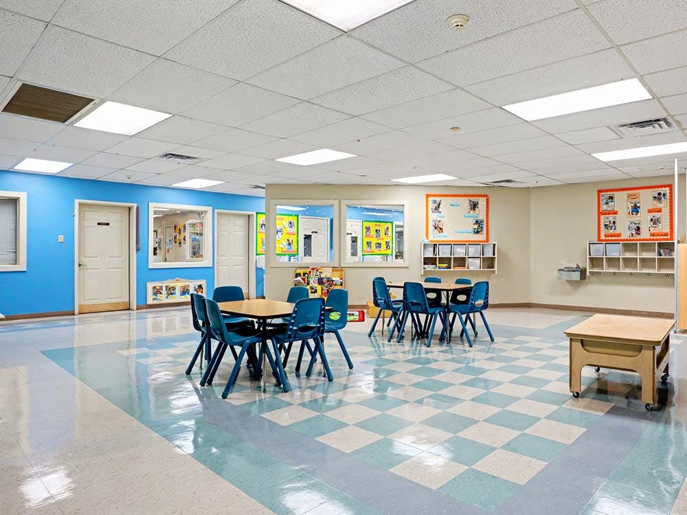 Empty classroom with small tables and chairs, and blue checkered floor