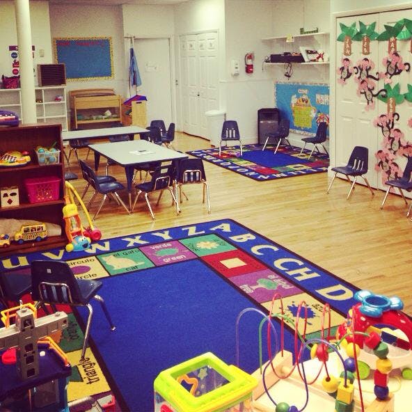 Playroom with tables, chairs, and colorful alphabet rugs
