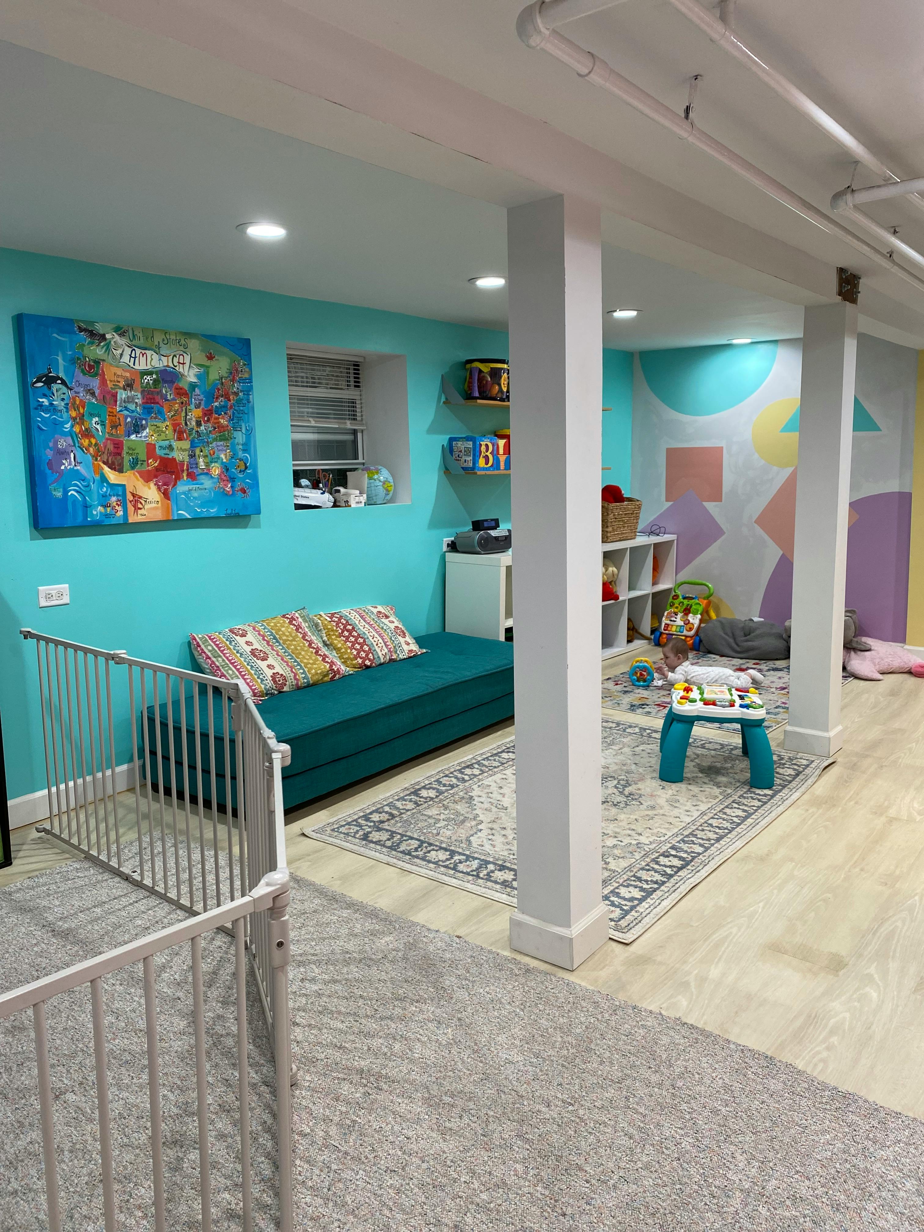 Basement playroom with a sofa, rug, and child's play area