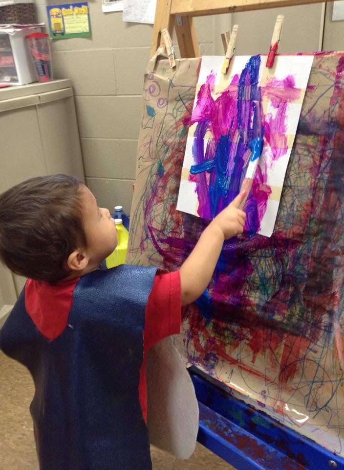 Child painting on an easel in a classroom