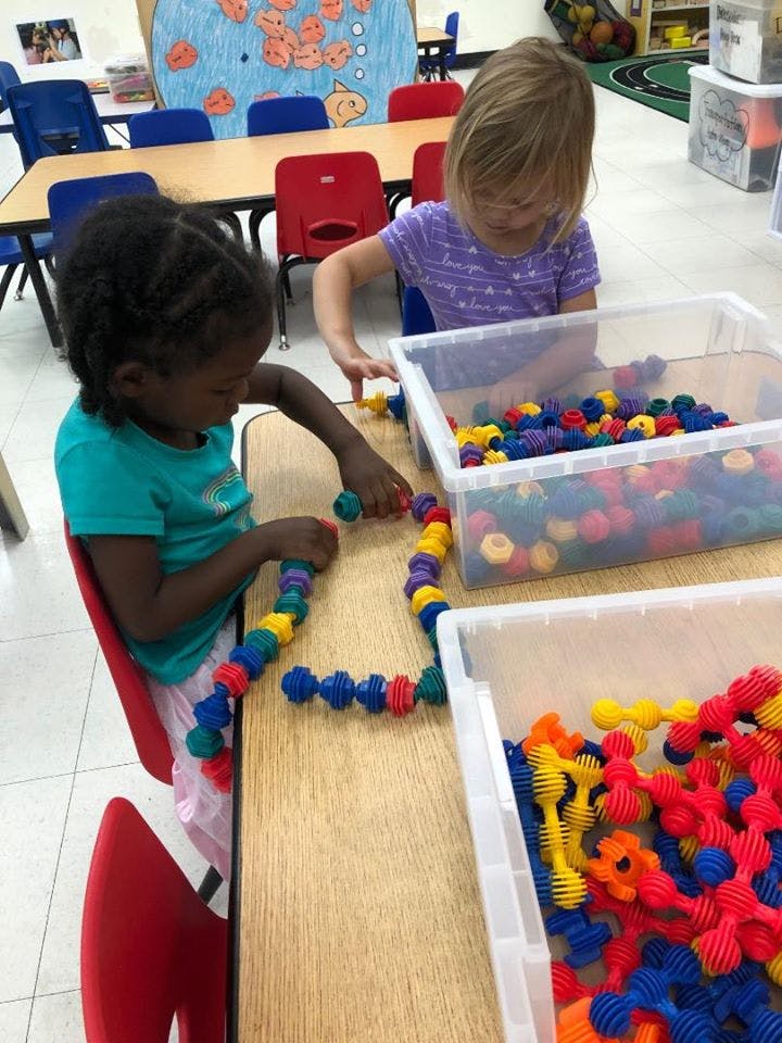 Two children playing with colorful interlocking toys at a table