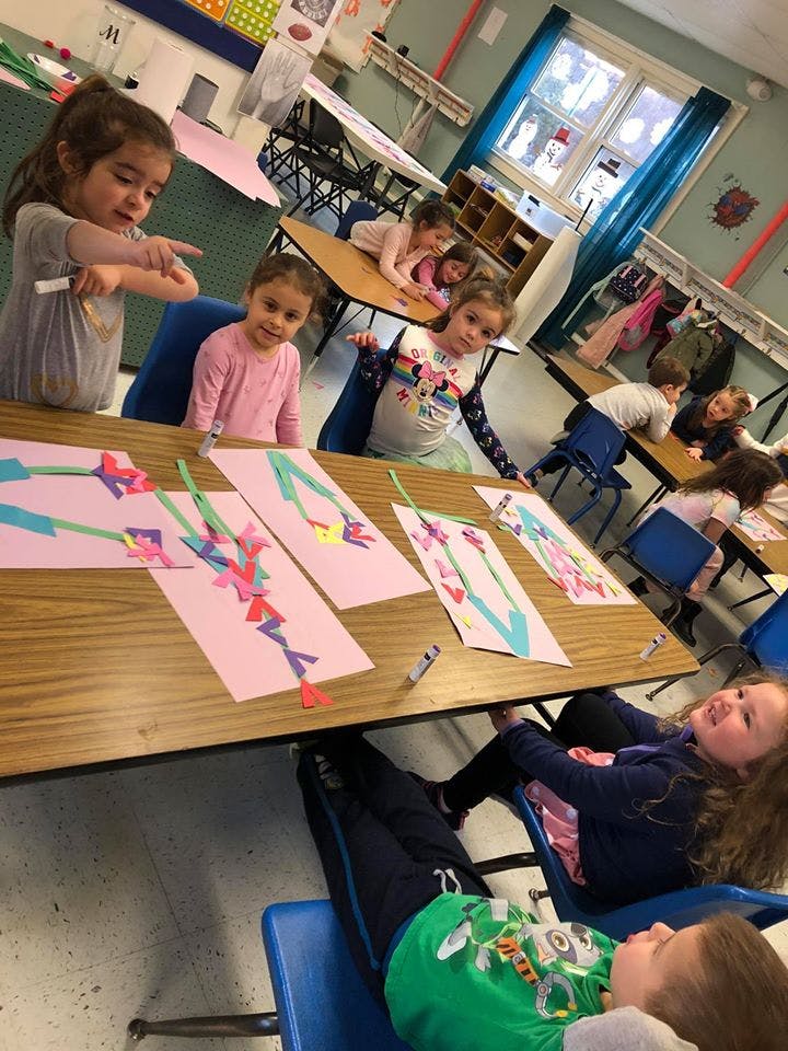 Children sitting at desks in a classroom with paper crafts