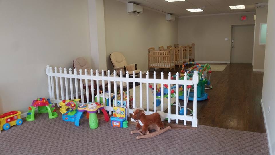 Play area with a white fence, toys, and a rocking horse