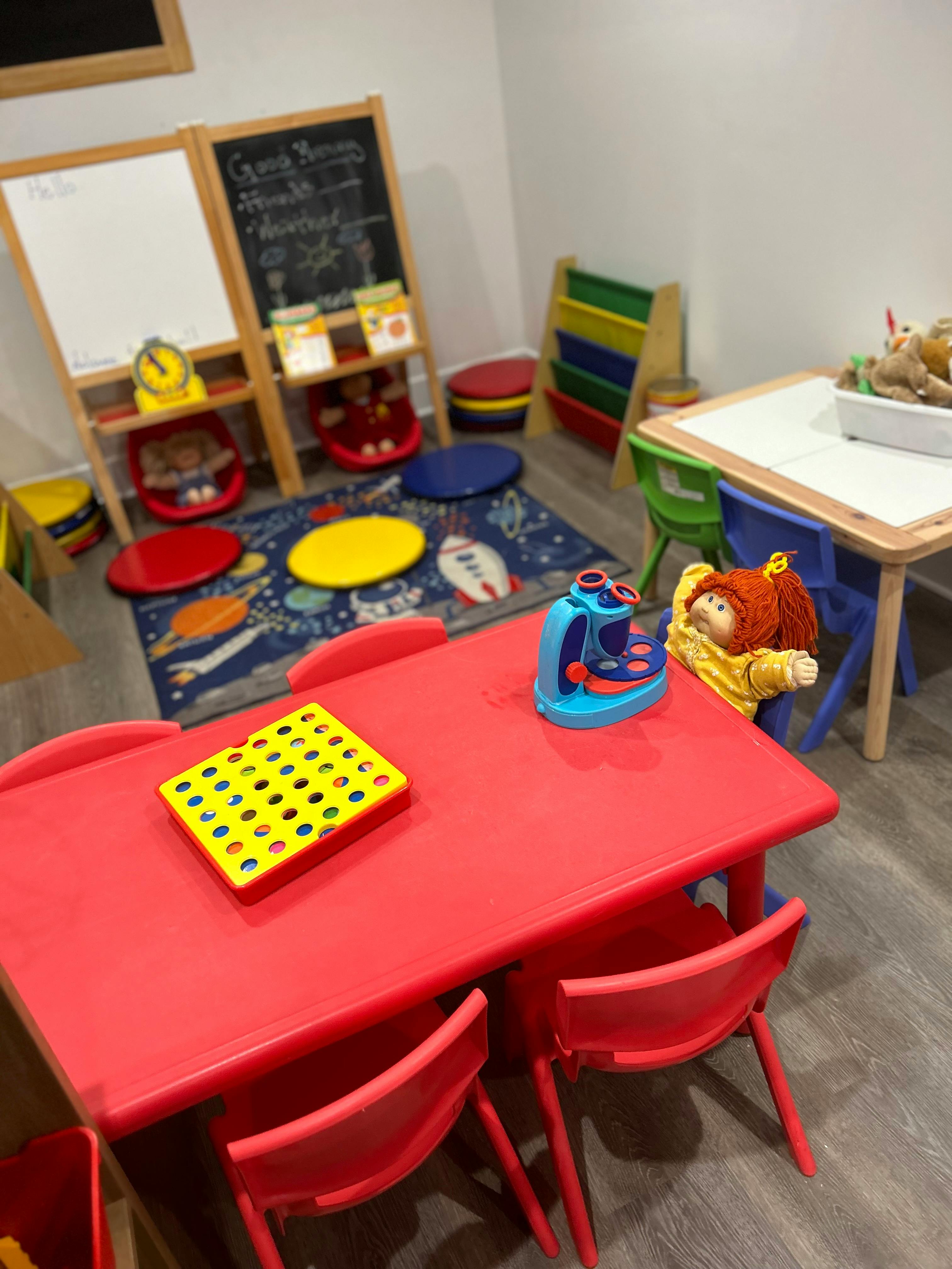 Playroom with small red table and chairs, toy microscope, and doll