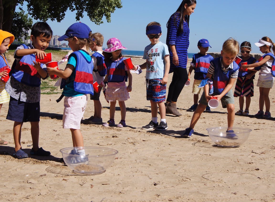 Children playing with cups and bowls on a sandy beach