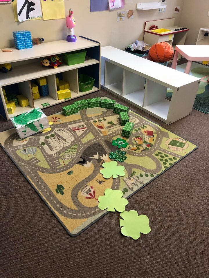 Playroom with a road map rug, shelves with toys, and green blocks