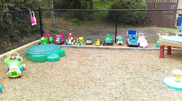 Playground with a green turtle sandbox and various toys lined-up toys