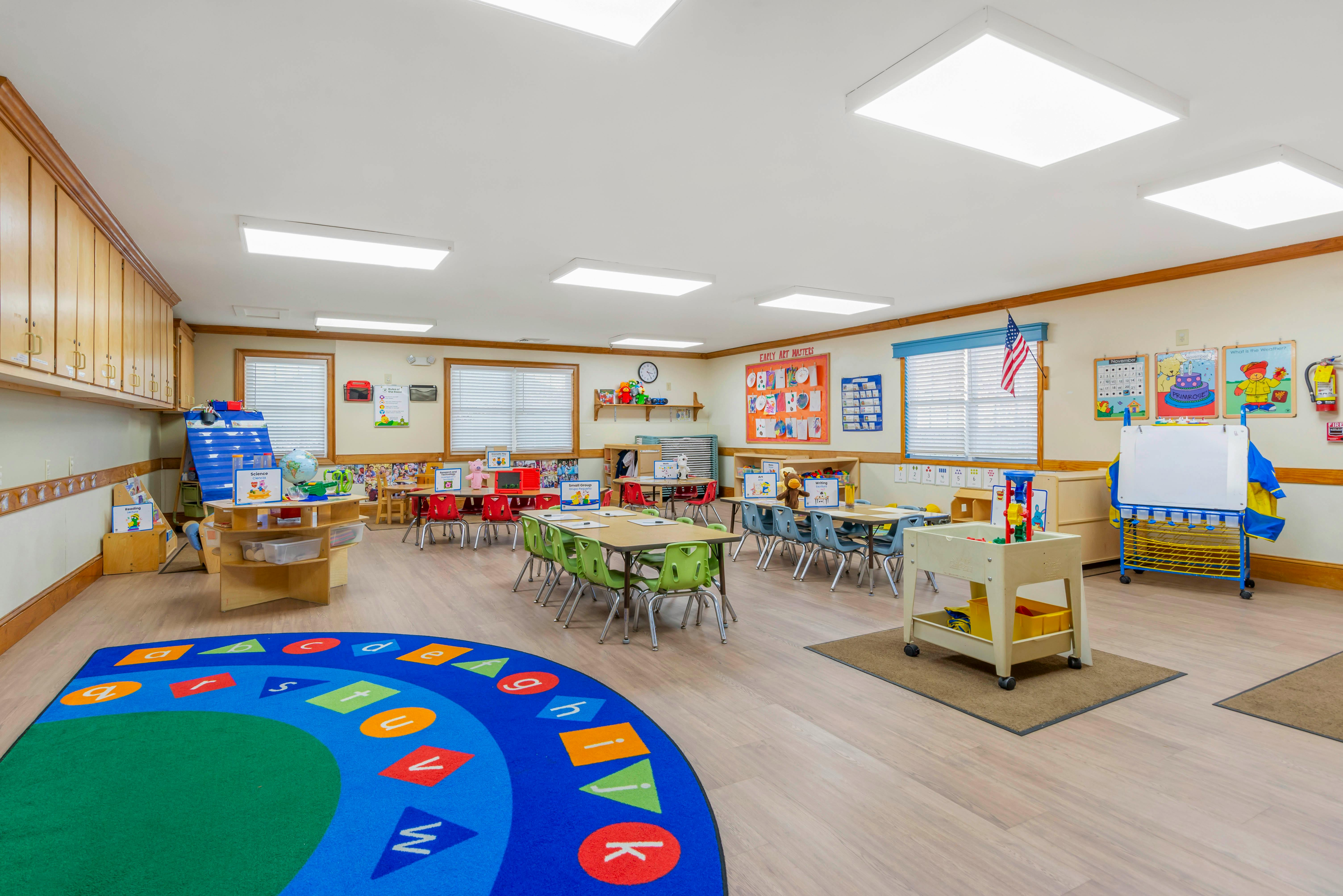 An empty early childhood classroom with multiple small tables and chairs