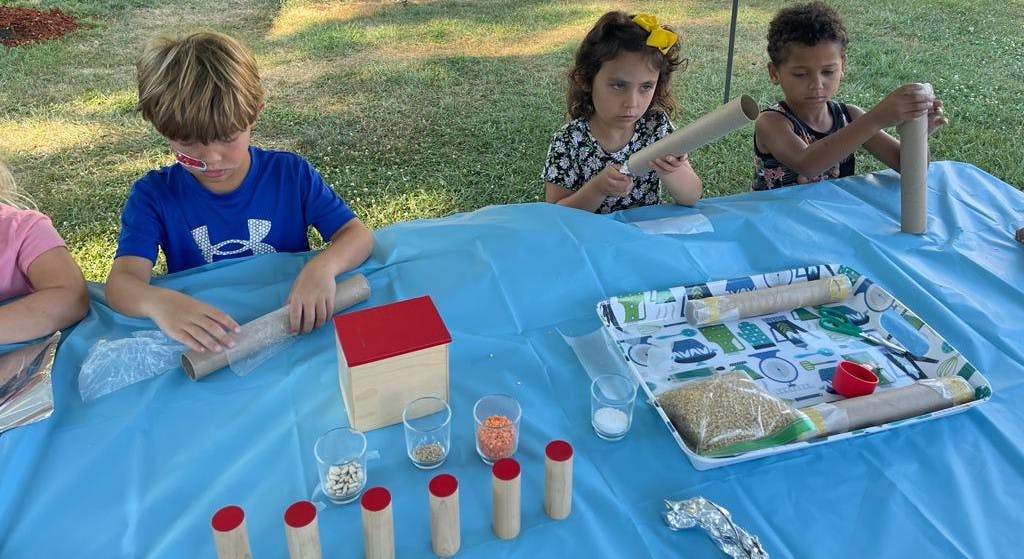Three children working on crafts with cardboard tubes and various materials