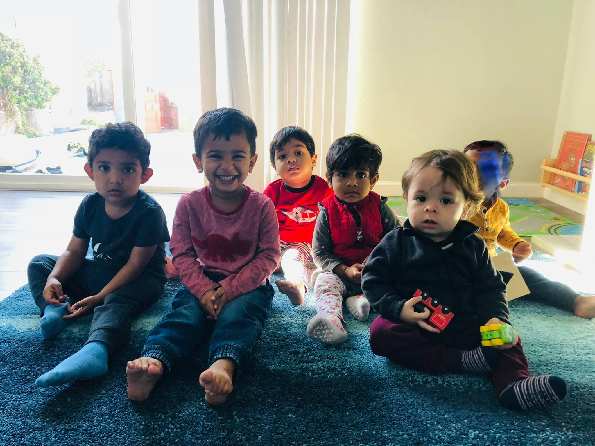 Group of children and teens sitting on a rug